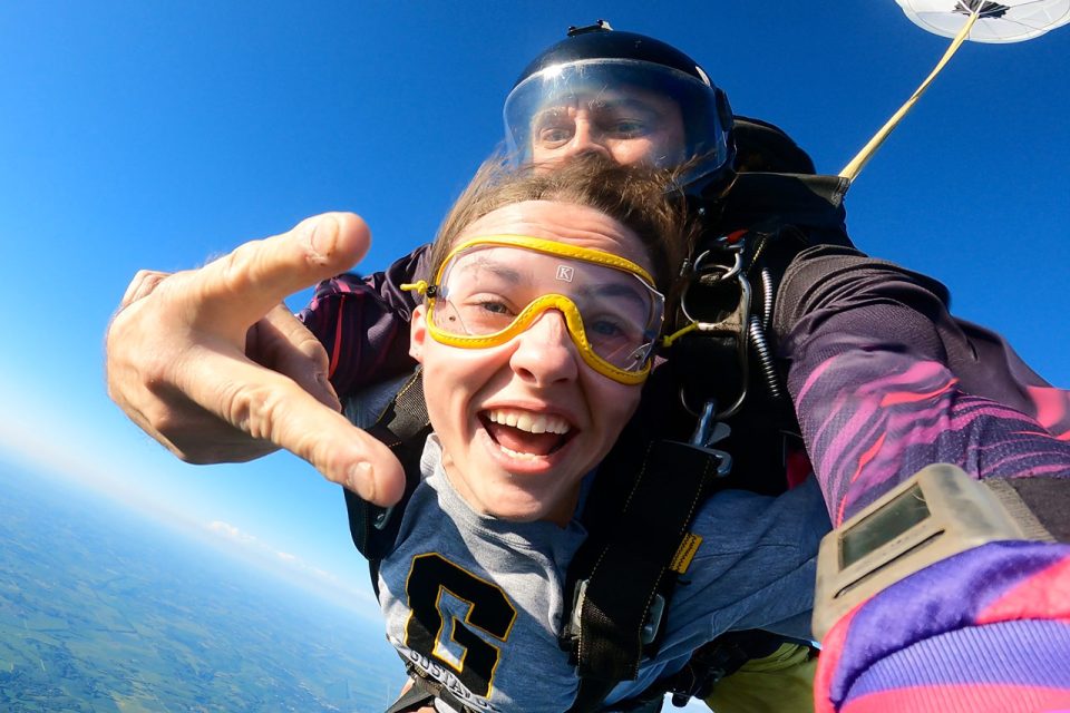 Tandem skydiving instructor chucking the deuces as he and his female tandem student skydive at Jump Omaha.