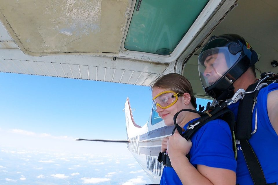 Male and female tandem skydiving pair at the aircraft door ready to exit the plane.