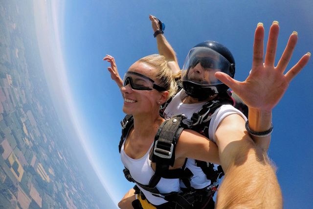 Male and female tandem pair wearing white shirts skydiving with joy!
